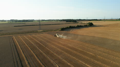 Establishing-Drone-Shot-of-Combine-Harvester-in-Dust-at-Golden-Hour-Dusk-Sunset