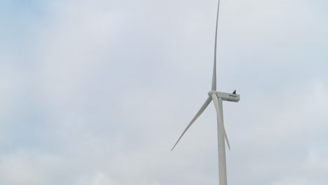 Isolated-turbine-with-its-blades-spinning-against-the-sky-in-Europe,-copy-space-background-of-renewable-energy-concept
