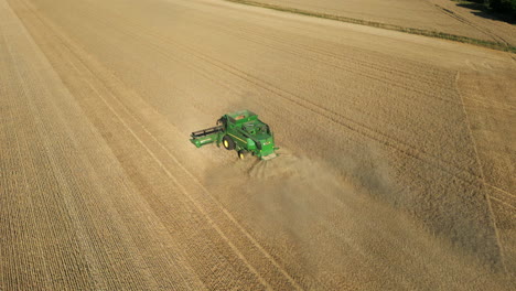 Falling-Establishing-Drone-Shot-of-Green-John-Deere-Combine-Harvester-Harvesting-Spraying-Dust-Behind-on-Sunny-Summer-Day-UK