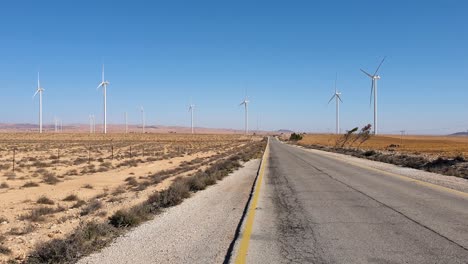 Sustainable-and-clean-energy-generation-from-wind-turbine-farm-with-long,-straight-road-in-Arabian-desert-landscape-of-Jordan,-Middle-East