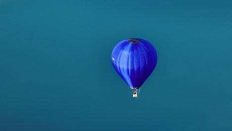 Aerial-view-of-a-hot-air-balloon-with-turquoise-lake-behind