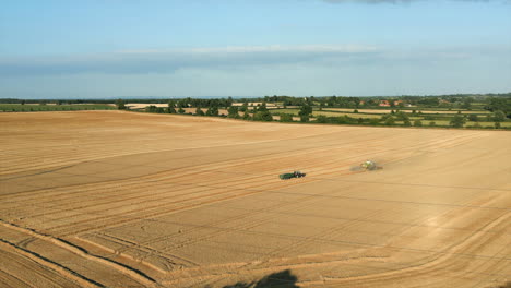 Zooming-Establishing-Drone-Shot-of-Combine-Harvester-and-Tractor-with-Trailer-with-Power-Lines-in-the-Foreground-at-Golden-Hour-UK