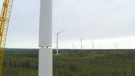 Orbital-shot-of-workers-assembling-the-mast-tower-of-a-wind-turbine-during-its-construction