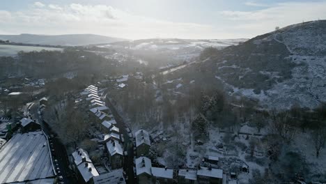 Cold-Snowy-Winter-Cinematic-aerial-view-cityscape-townscape-with-snow-covered-roof-tops-Panorama-small-rural-town-of-Delph-Village-West-Yorkshire,-Endland