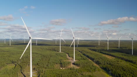 Wind-turbine-farm-panning-shot-landscape-during-a-sunny-day-against-a-blue-sky,-aerial-view