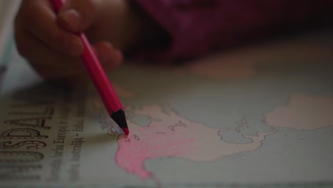 A-toddler-girl-is-coloring-the-continent-of-North-America-with-a-pink-pencil-in-a-World-Atlas-educational-book-2