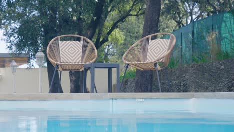 Rotating-shot-of-two-white-wicker-poolside-chairs