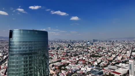 Mítikah-Tower-tallest-building-in-Mexico-city,-bright,-sunny-day-in-Benito-Juarez---Descending,-aerial-view