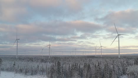 Scenic-landscape-of-wind-turbines-in-wind-farm-during-winter-at-forest-with-snow,-panoramic-view