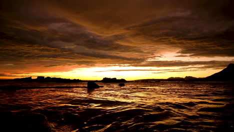 Fire-sunset-over-ocean,-orange-illuminated-cloudscape,-liquid-gold-sea-surface