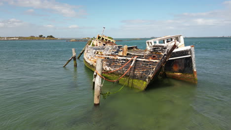 Two-abandoned-shipwreck-moored-near-coastline-of-New-Zealand,-orbiting-view