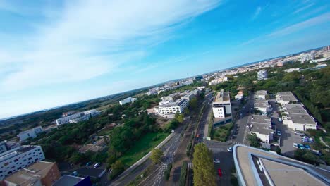 FPV-aerial-view-of-Montpellier,-going-between-the-buldings-following-the-cars-driving-on-the-street