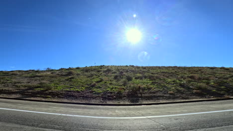 Looking-out-the-passenger-window-of-a-car-on-California-State-Route-14-passing-green-rolling-grassland-hills