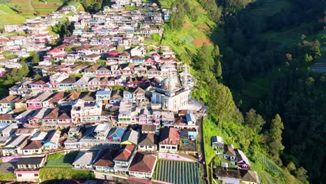 Drone-shot-of-colorful-houses-located-on-mountain,-mosque-and-plantation-fields-during-sunset---Butuh,Indonesia