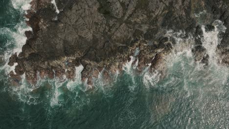 Top-down-View-Of-Ocean-Waves-Crashing-On-Rocky-Shore-Of-Beach-In-Guanacaste,-Costa-Rica---aerial-drone-shot