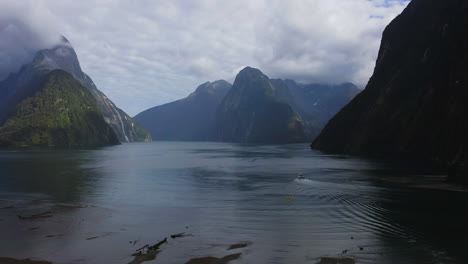 Milford-Sound-Fjordland-drone-shot-of-the-ocean-with-with-mountains-all-around-in-New-Zealand