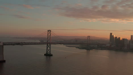Rising-circling-aerial-shot-of-Bay-Bridge-at-golden-hour
