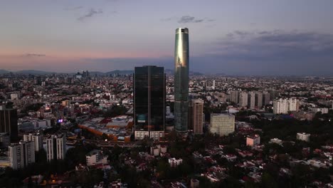 Aerial-view-approaching-the-Mitikah-building,-dusk-in-Coyoacan,-Mexico-city