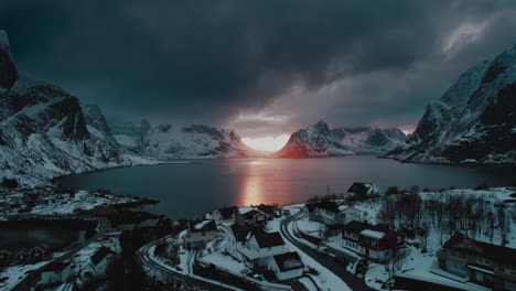 Drone-Flight-over-Reine,-Norway-at-Sunset-with-Blue-Dark-Clouds-and-Winter-Ocean-View---A-Surreal-Aerial-Footage
