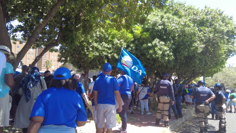 A-reverse-tracking-shot-of-a-protestor-holding-a-Democratic-Alliance-party-flag-at-a-march-against-Eskom's-load-shedding-and-rolling-blackouts