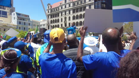 Democratic-Alliance-supporters-wave-flags-and-signs-to-protest-Eskom's-load-shedding-and-rolling-blackouts-as-a-politician-makes-a-speech