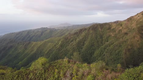 Mountain-ridge-hiking-trail-in-Hawaii-Kai-east-Honolulu-being-hit-by-the-morning-golden-light-overlooking-the-North-Pacific-Ocean,-aerial-orbit