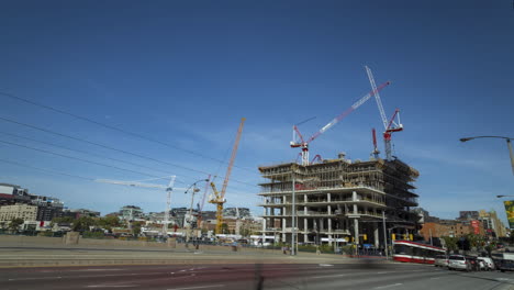 Timelapse-of-construction-and-crane-movement-with-vehicle-traffic-in-the-foreground