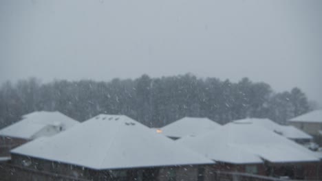 snow-falling-quickly-with-a-suburban-neighborhood-and-trees-in-the-background