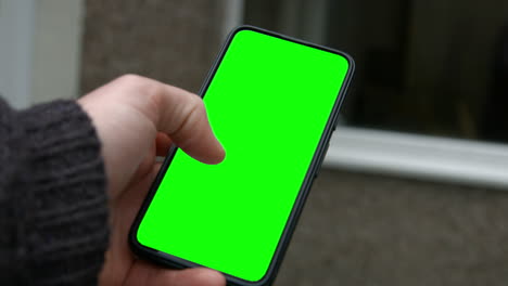 Männliche-Hand,-Die-Smartphone-Green-Screen-Ersatz-Mit-Daumen-Hält,-Der-Durch-4k-Wischt