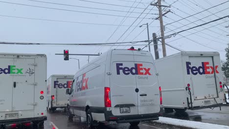 Several-FedEx-trucks-at-a-stopped-at-a-traffic-light-on-a-cloudy-day