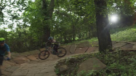 two-bicyclists-riding-through-a-forest-on-a-trail