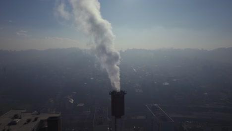 Rauch-Aus-Einem-Schornstein-Mit-Einer-Verschmutzten-Stadt-Im-Hintergrund