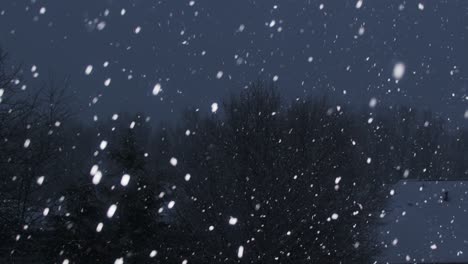 January-snowfall-on-a-dark-evening,-panning-from-right-to-left,-with-trees-and-houses-in-the-background