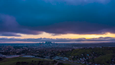 Drone-hyperlapse-during-sunset-over-a-Los-Angeles-suburb-with-downtown-skyline-silhouette-in-the-distance