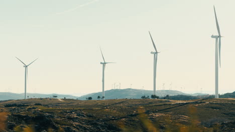 A-wide-shot-of-a-field-of-wind-turbines-in-a-state-of-readiness-amidst-the-natural-beauty-of-the-mountains