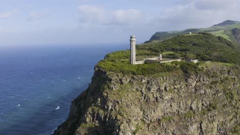 drone-footage-with-dolly-camera-movement-of-a-Lighthouse-revealing-dramatic-cliffs-and-the-Atlantic-Ocean,-São-Jorge-island,-the-Azores,-Portugal