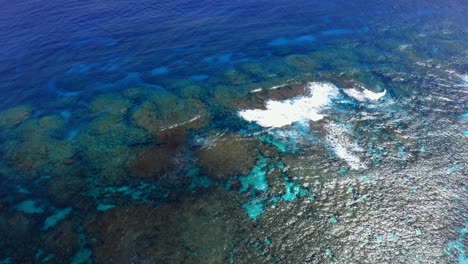 A-drone-view-provided-by-the-drone-shows-the-idyllic-blue-lagoon,-its-transparency-revealing-the-hidden-beauty-of-the-rocks-and-sea-life,-while-the-waves-crashing-on-the-reef