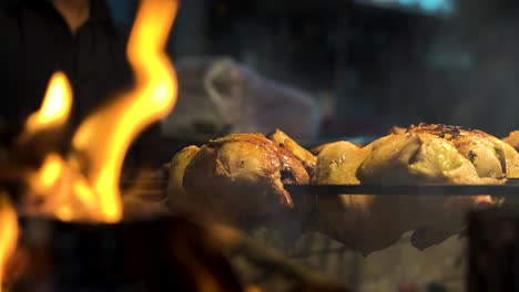 Close-up-of-chicken-grill-on-the-very-hot-charcoal-burning-in-a-grill-in-slow-motion-and-flames