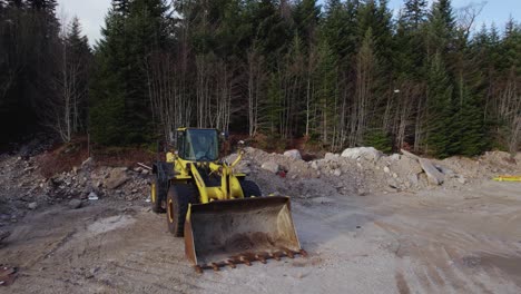 Circling-around-bulldozer-on-a-construction-site-with-forest-in-the-background