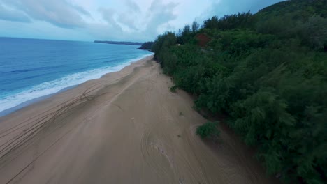 Cinematic-drone-shot-of-amazing-white-sand-beach-and-tropical-coral-reef-lagoon-towards-beautiful-green-mountains-on-Kauai