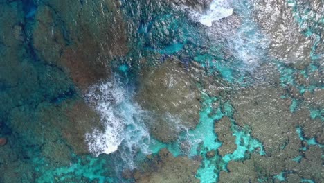 A-drone-captures-a-shot-of-a-blue-lagoon,-showcasing-the-crystal-clear-waters-that-reveal-the-stunning-underwater-landscape,-