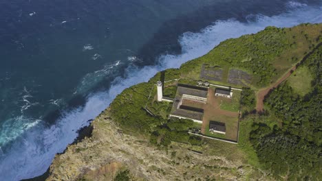 top-down-drone-footage-of-a-Lighthouse-on-the-edge-of-dramatic-cliffs-with-the-Atlantic-Ocean-in-the-background,-São-Jorge-island,-the-Azores,-Portugal