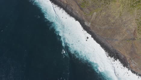 Top-down-drone-footage-of-waves-crashing-on-dramatic-cliffs-over-the-Atlantic-Ocean-in-Sao-Jorge-island,-Azores,-Portugal