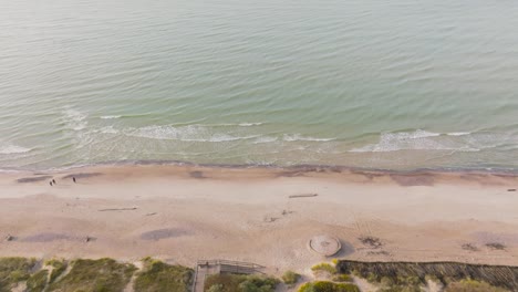An-aerial-view-The-water-of-the-Baltic-Sea-washes-the-beach-where-people-walk-on-a-quiet-autumn-afternoon