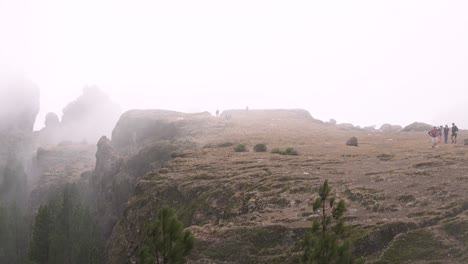 Hiking-group-ascending-to-Roque-Nublo-duroing-a-misty-morning-in-Gran-Canary-Island,-Spain