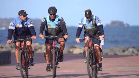 Gran-Canaria,-Spain---January-26-2023:-Policemen-riding-bikes-at-the-beach-in-Canary-Islands-in-Gran-Canaria