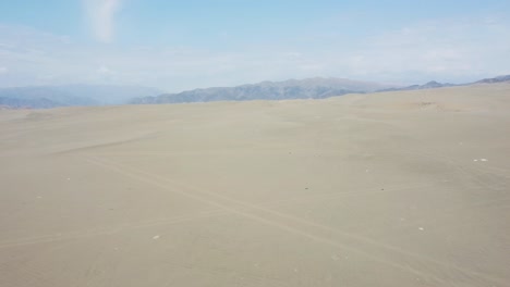 Drone-flies-forward-above-sand-dunes-in-desert