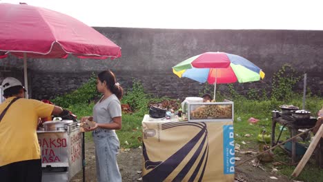 Straßenverkäufer-In-Bali-Beach,-Fleischbällchen-Und-Frittierte-Snacks-Indonesien-Lokaler-Markt-Traditionelle-Regenschirme-Und-Leute-Kaufen-In-Sukawati,-Vollmond,-Gianyar