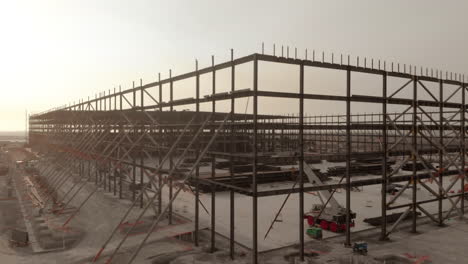 Metal-warehouse-structure-at-a-construction-site-in-a-cloudy-sunset
