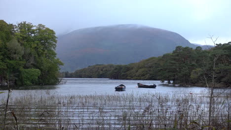 Two-boats-floating-on-calm-Muckross-Lake-in-County-Kerry,-Ireland